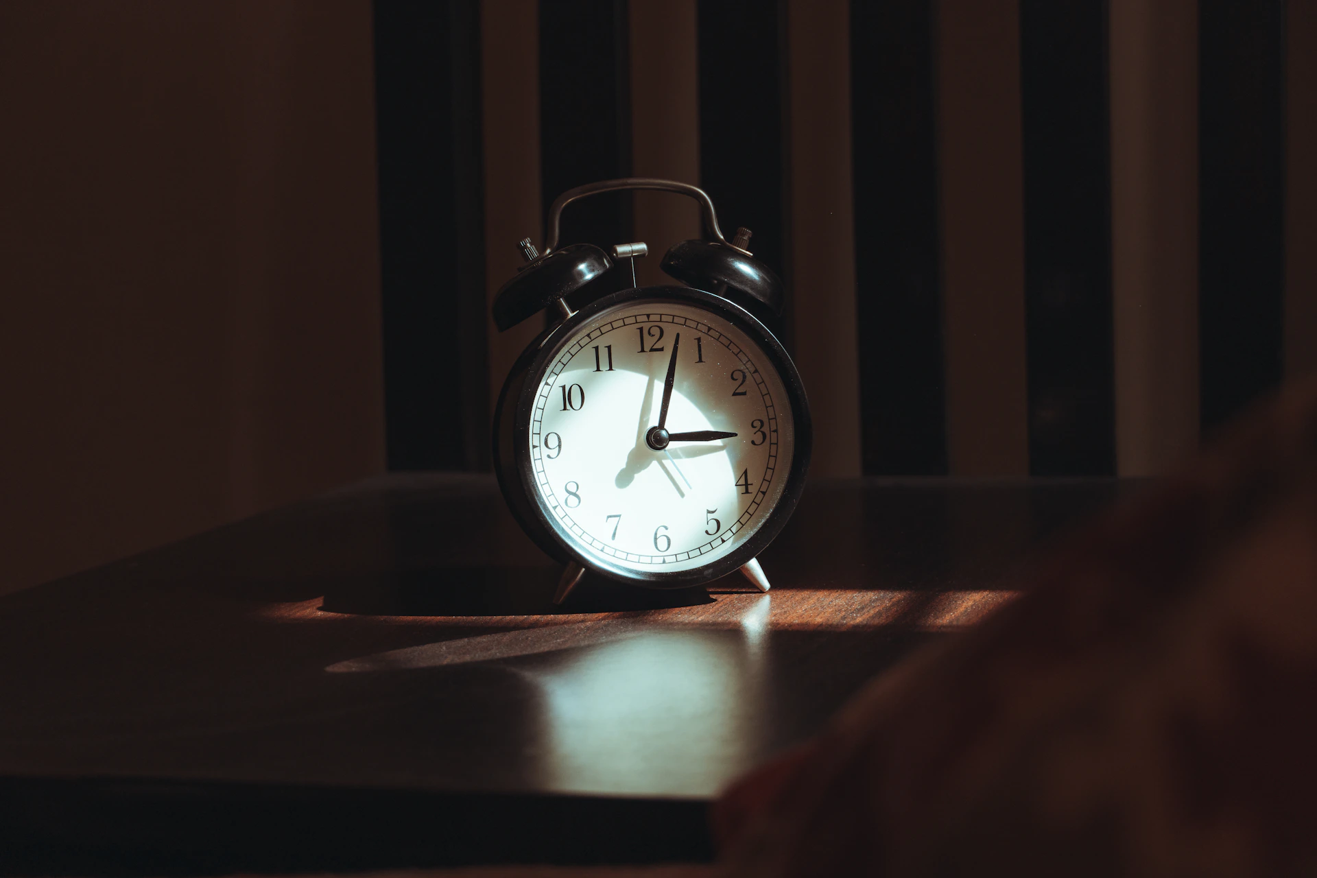 Alarm clock on a bedside table in a dark bedroom