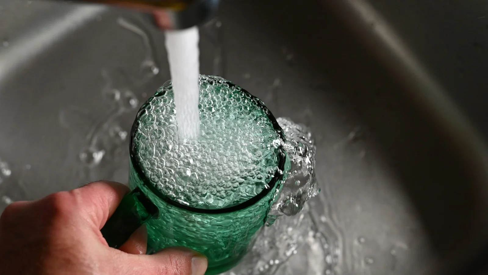 Personne remplissant une bouteille d'eau réutilisable au robinet